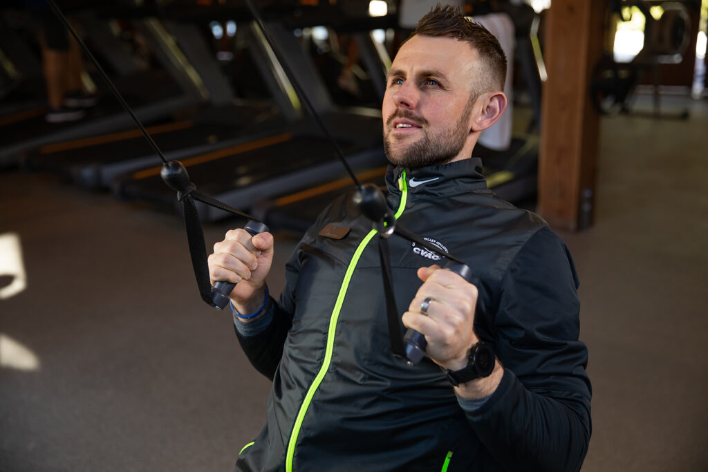 Kevin, a Personal Trainer, performs an exercise on a CVAC workout machine in the fitness center. He gives an inspiring look of determination, yet calm
