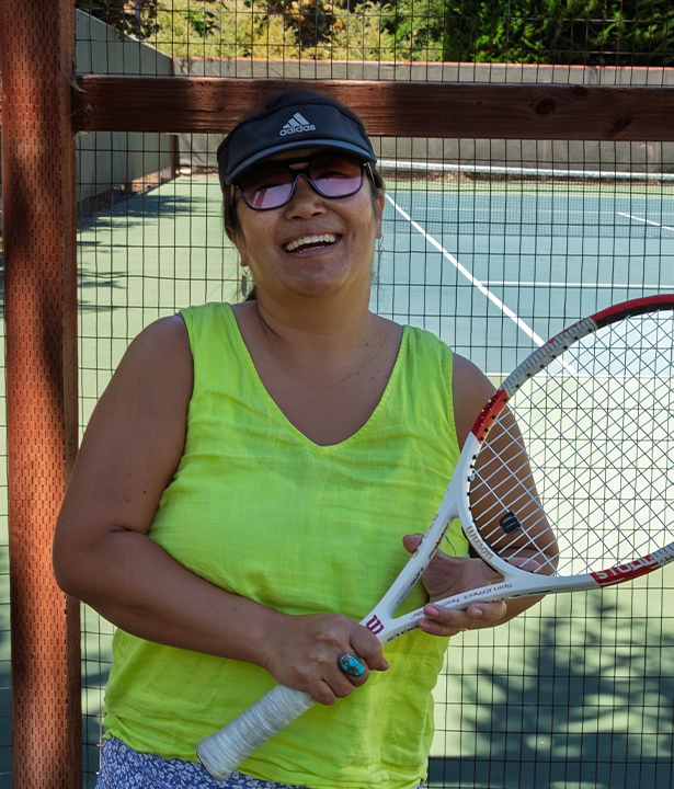A photo of Tennis Pro, Mio, smiling at CVAC, while holding a racket.