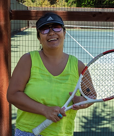 A photo of Tennis Pro, Mio, smiling at CVAC, while holding a racket.
